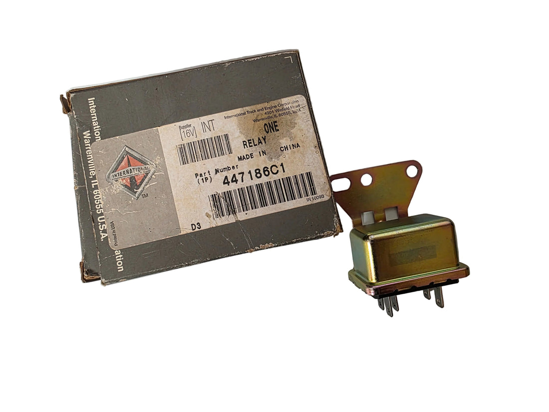 A vintage automotive relay next to its original paper packaging box. The box is gray with a white barcode label showing the brand 'International' and part number '447188C1'.