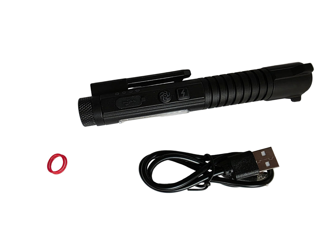 A black tactical LED flashlight with a textured grip and clip, shown alongside a black USB charging cable and a small clear plastic bag containing a red O-ring, all laid out on a white surface.