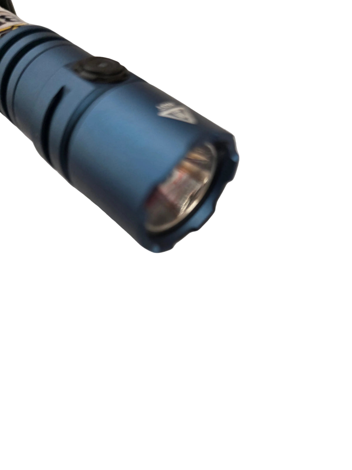 A close-up of a blue tactical flashlight with a textured body and a clear lens, resting on a wrinkled white surface.
