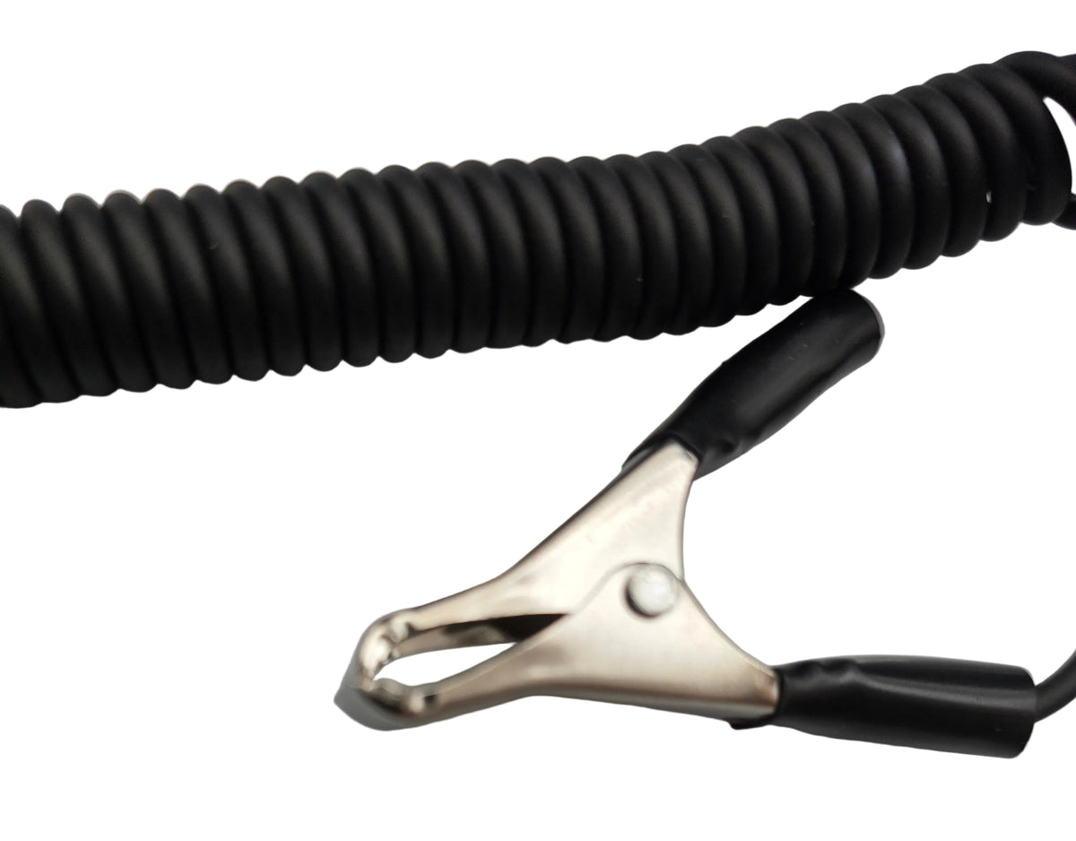 A close-up of a black coiled cable with a metal alligator clip and black protective sleeves on the clip, resting on a light gray surface.