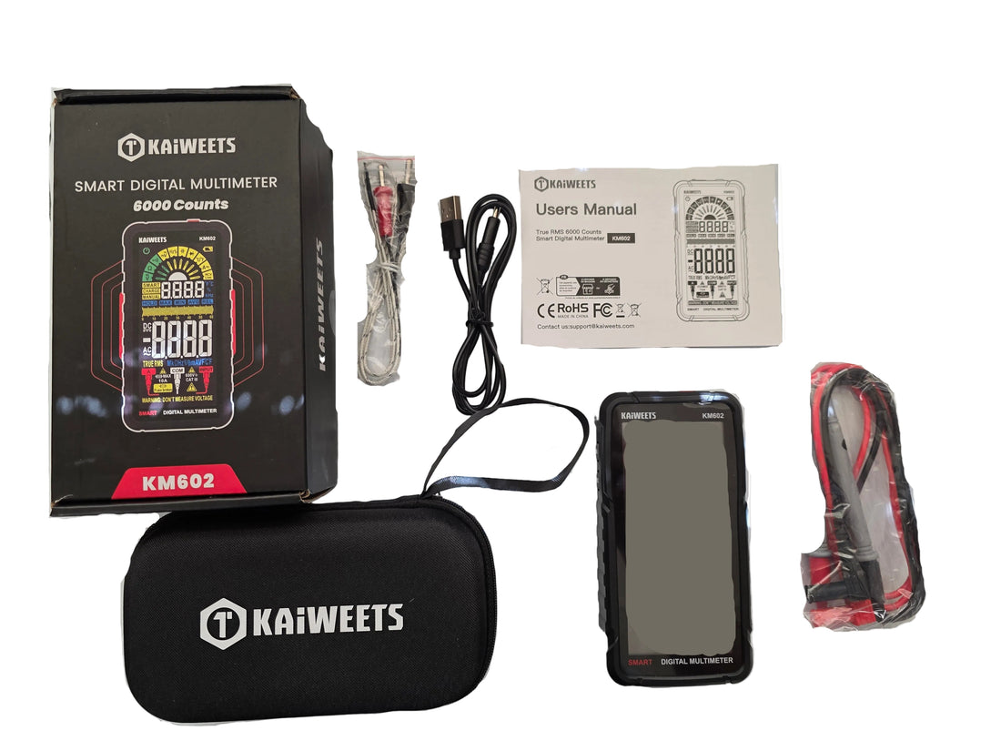 Kaiweets KM8002 smart digital multimeter kit with its black carrying case, retail box, USB cable, power adapter, user manual, and battery, laid out on a white sheet over a speckled gray countertop.
