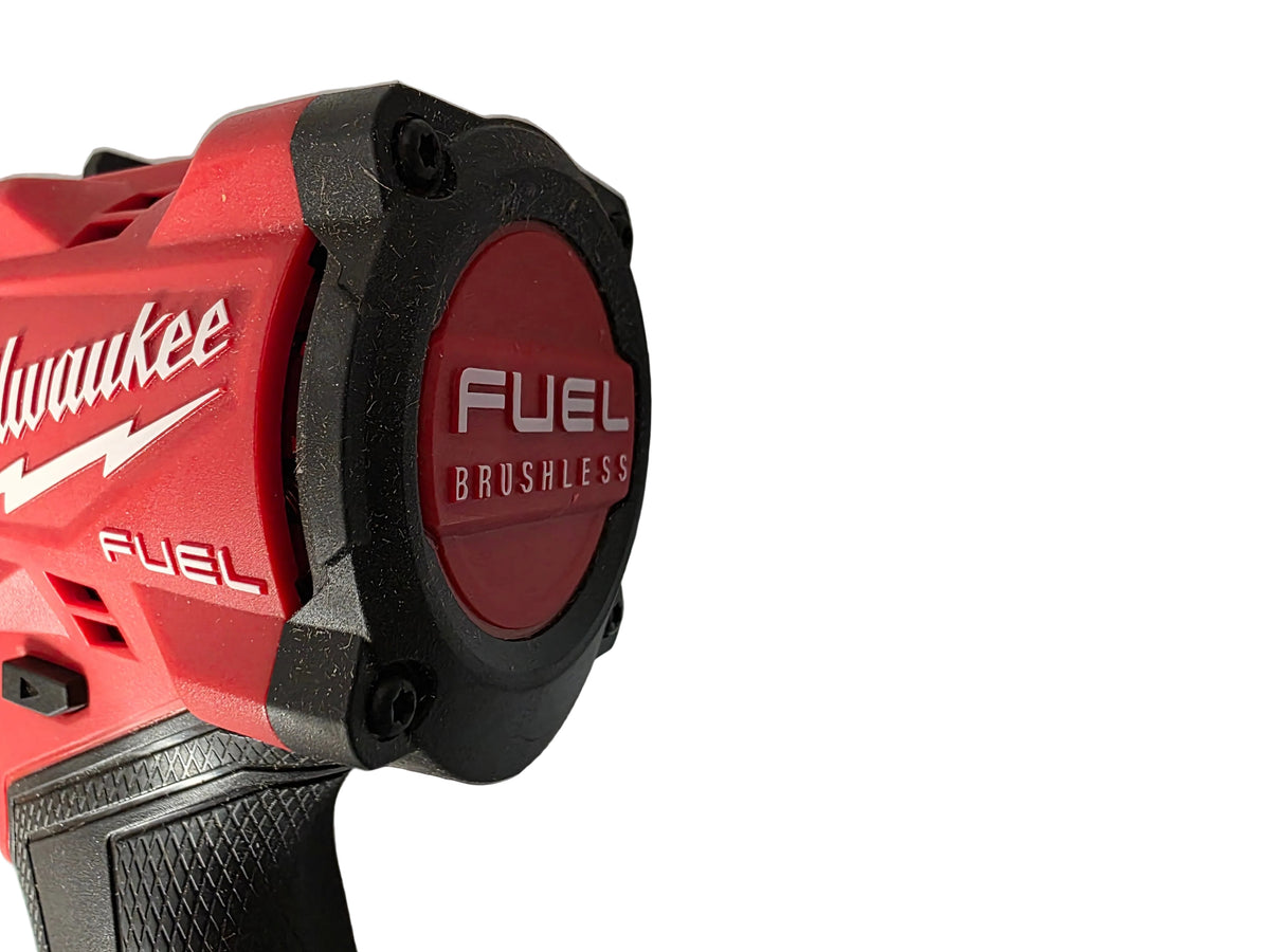 Close-up of a Milwaukee cordless drill or driver showing the red and black battery pack end with visible Milwaukee and Fuel branding, resting on a crinkled light gray surface.