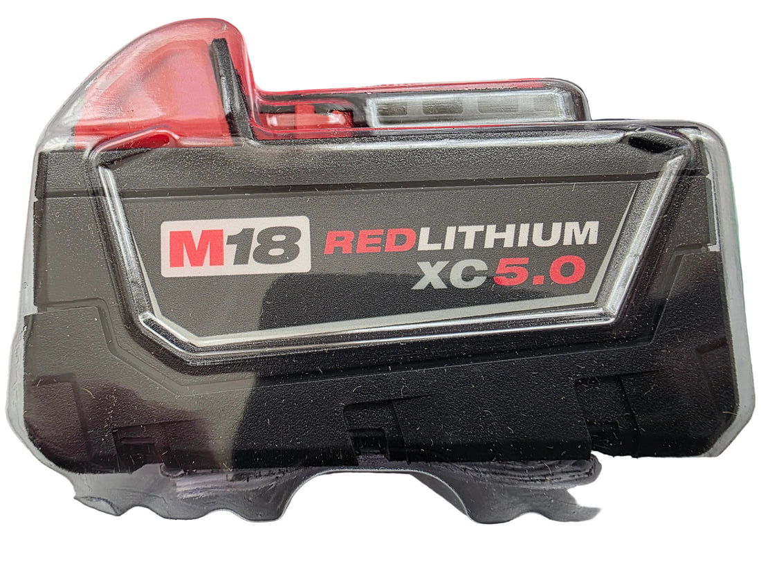 A M18 RED LITHIUM XC-5.0 cordless battery in its original clear plastic clamshell packaging, showing the black and red battery face.