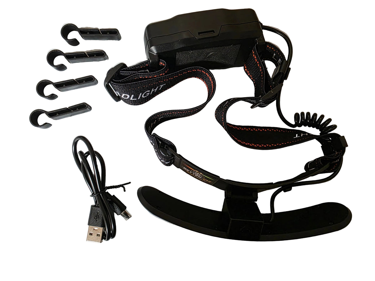 Black electronic headband device with attached earpieces, a USB charging cable, and four small black accessories laid out on a white background.