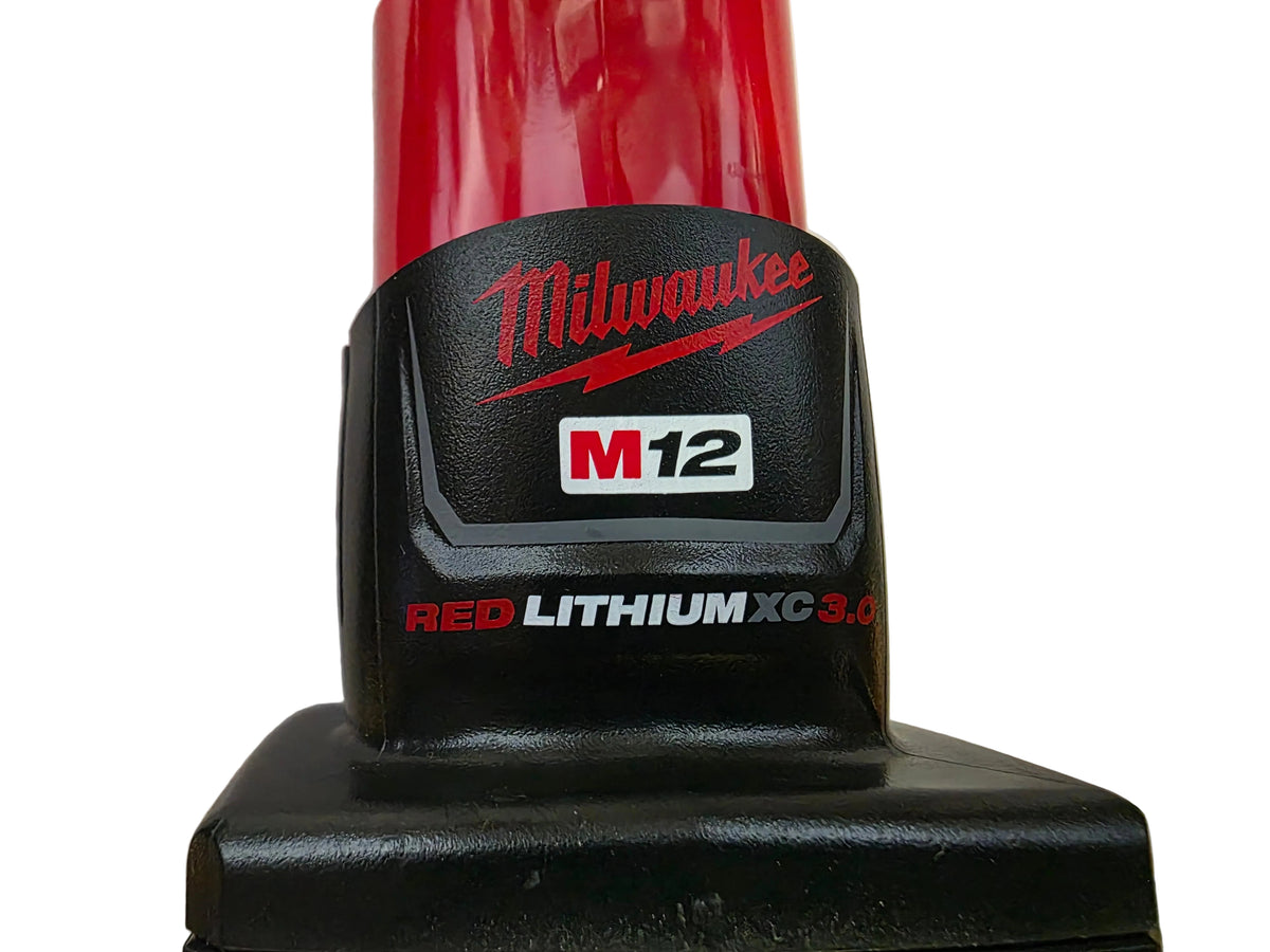Close-up of a Milwaukee M12 cordless tool battery pack, showing the black and red body with the Milwaukee logo and M12 label.