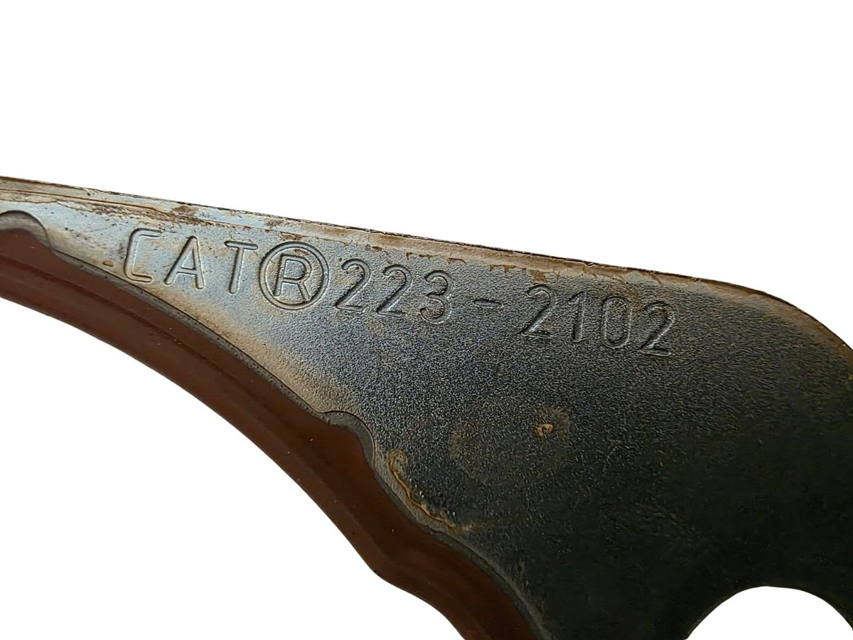 Close-up of a dark metal blade or tool component with embossed alphanumeric markings 'CATB223-2102' on a plain white background.
