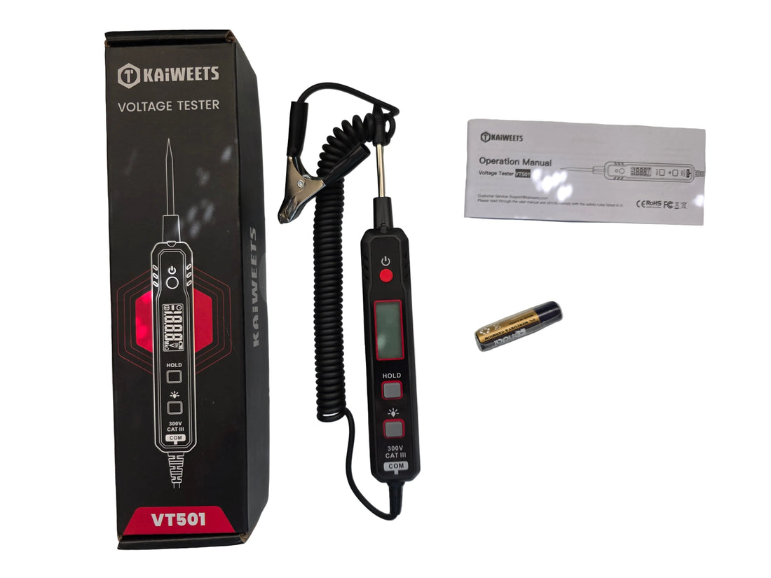A handheld digital voltmeter with a coiled cord and metal clip, shown with its black retail box, a small battery, and a paper manual on a light reflective surface.