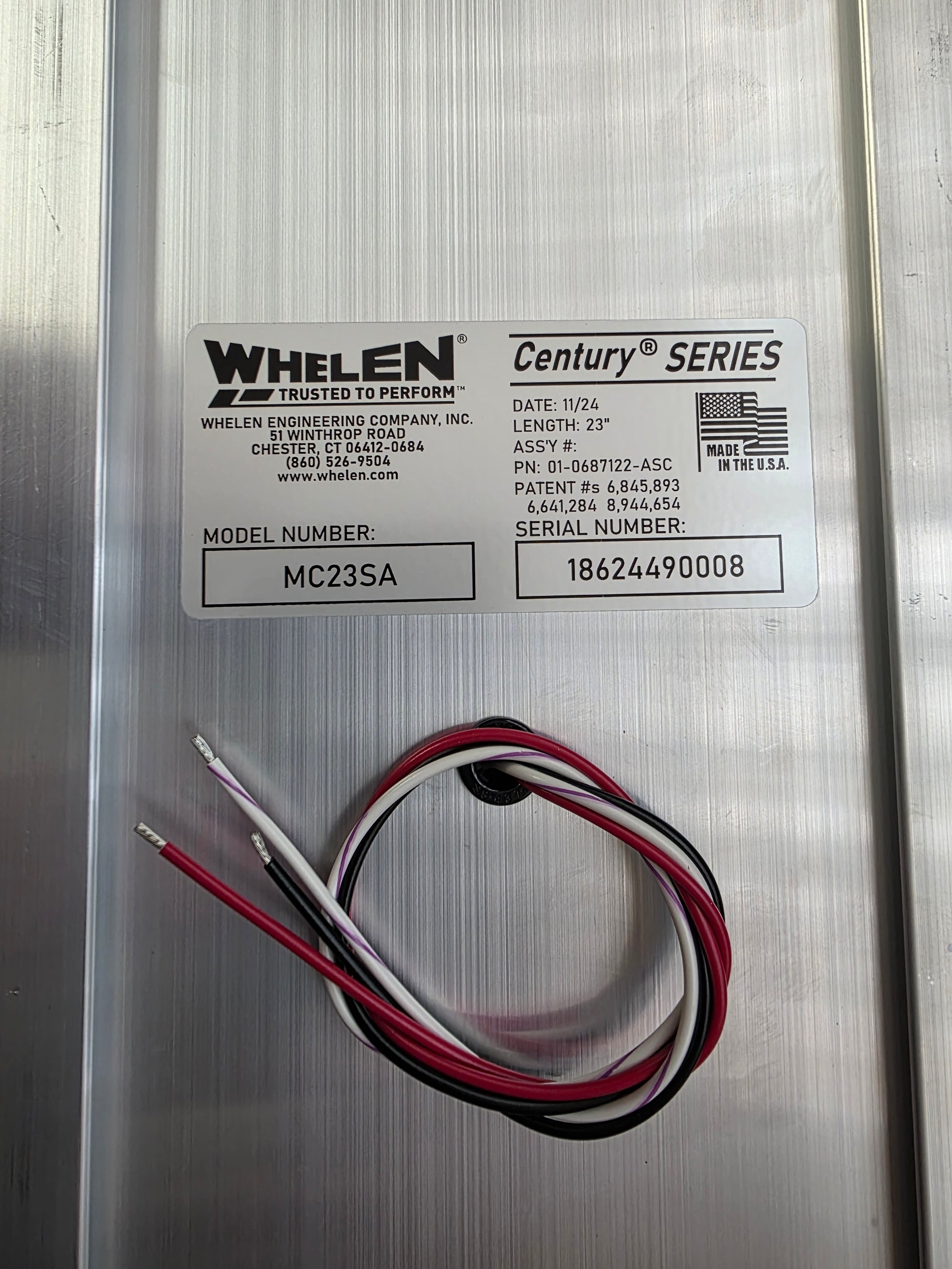 Metallic panel with Whelen label and wiring on a metallic background