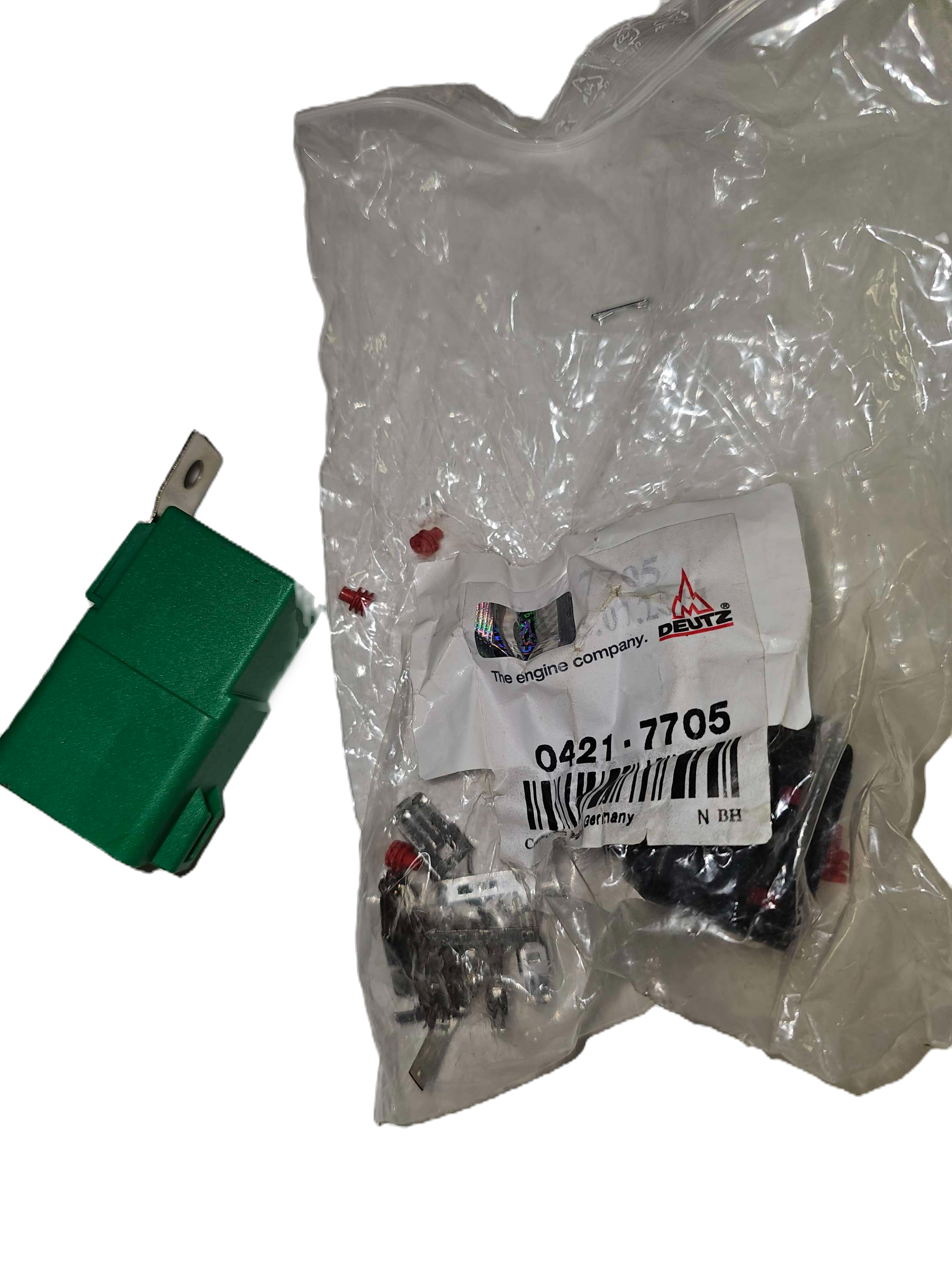 Green switch next to a plastic bag with automotive parts and a label.