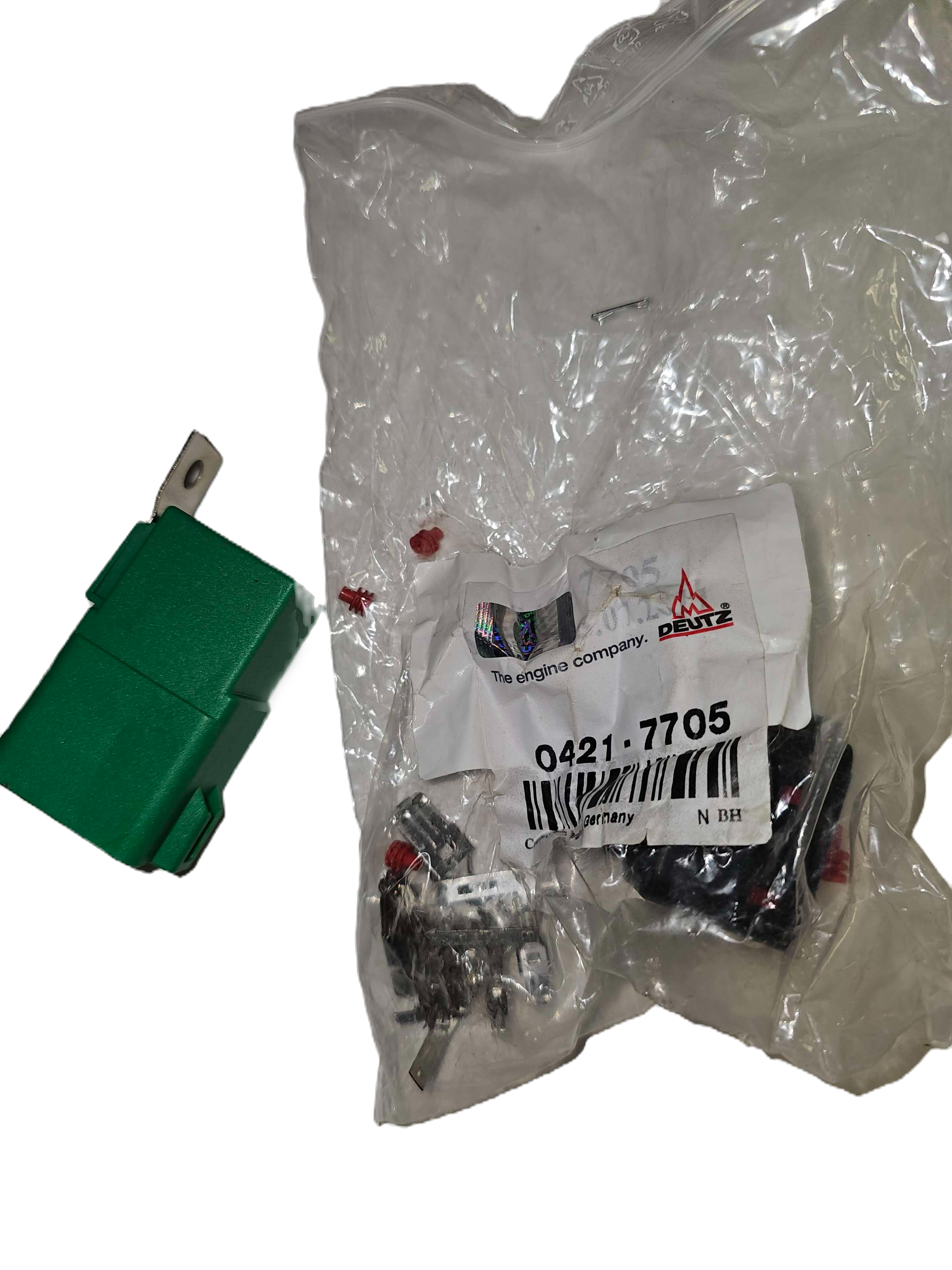 Green switch next to a plastic bag with automotive parts and a label.