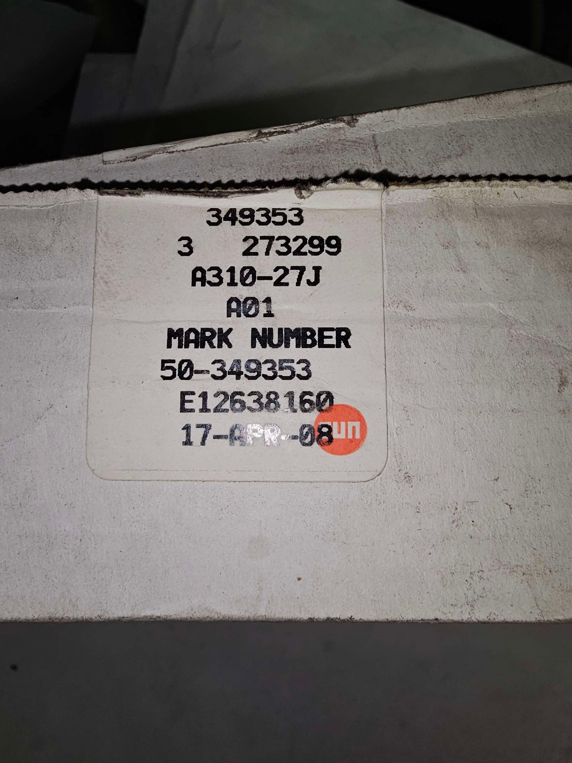Label with text and a logo on a cardboard surface