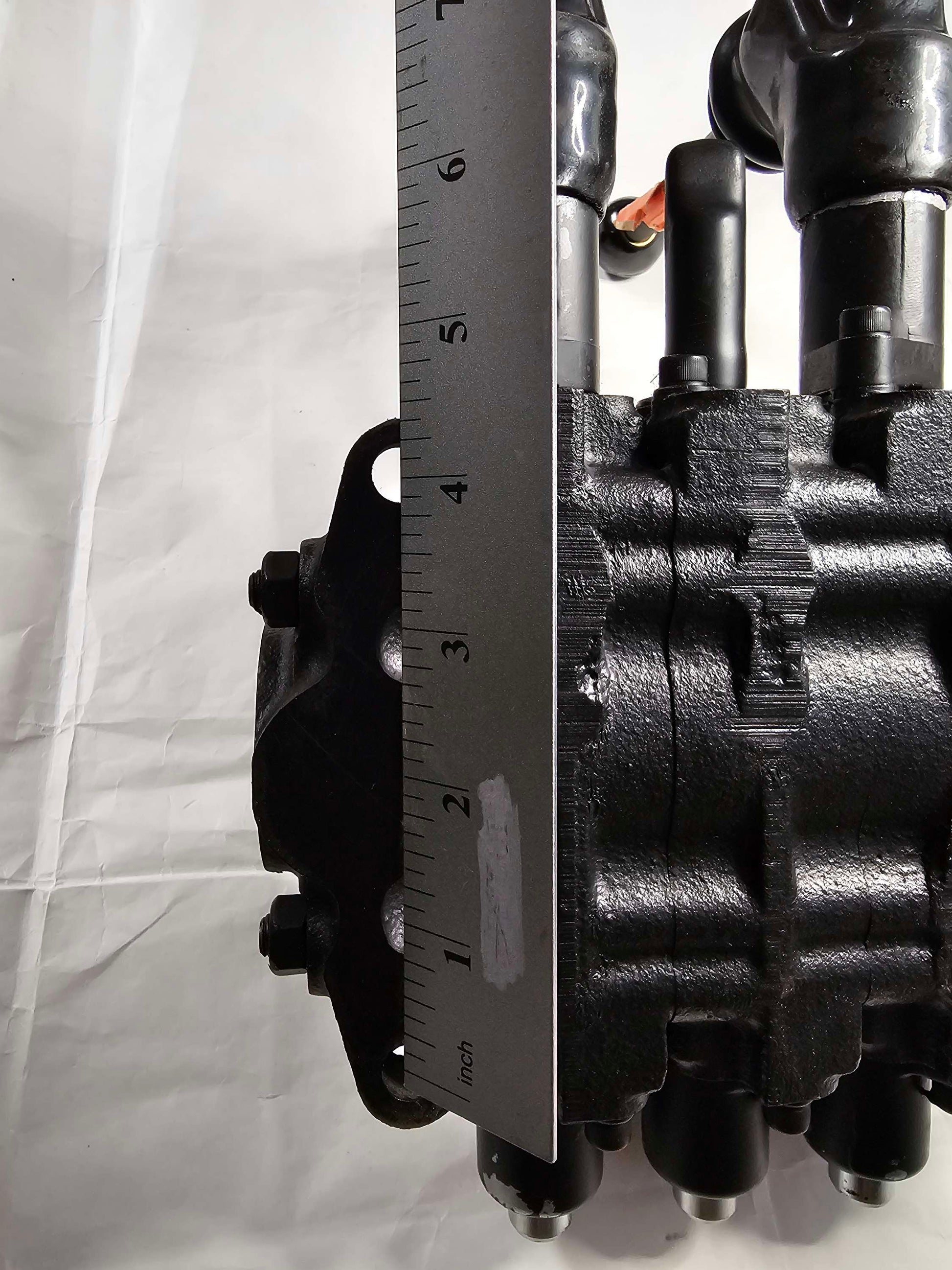 Close-up of a mechanical component with a ruler for scale on a white background