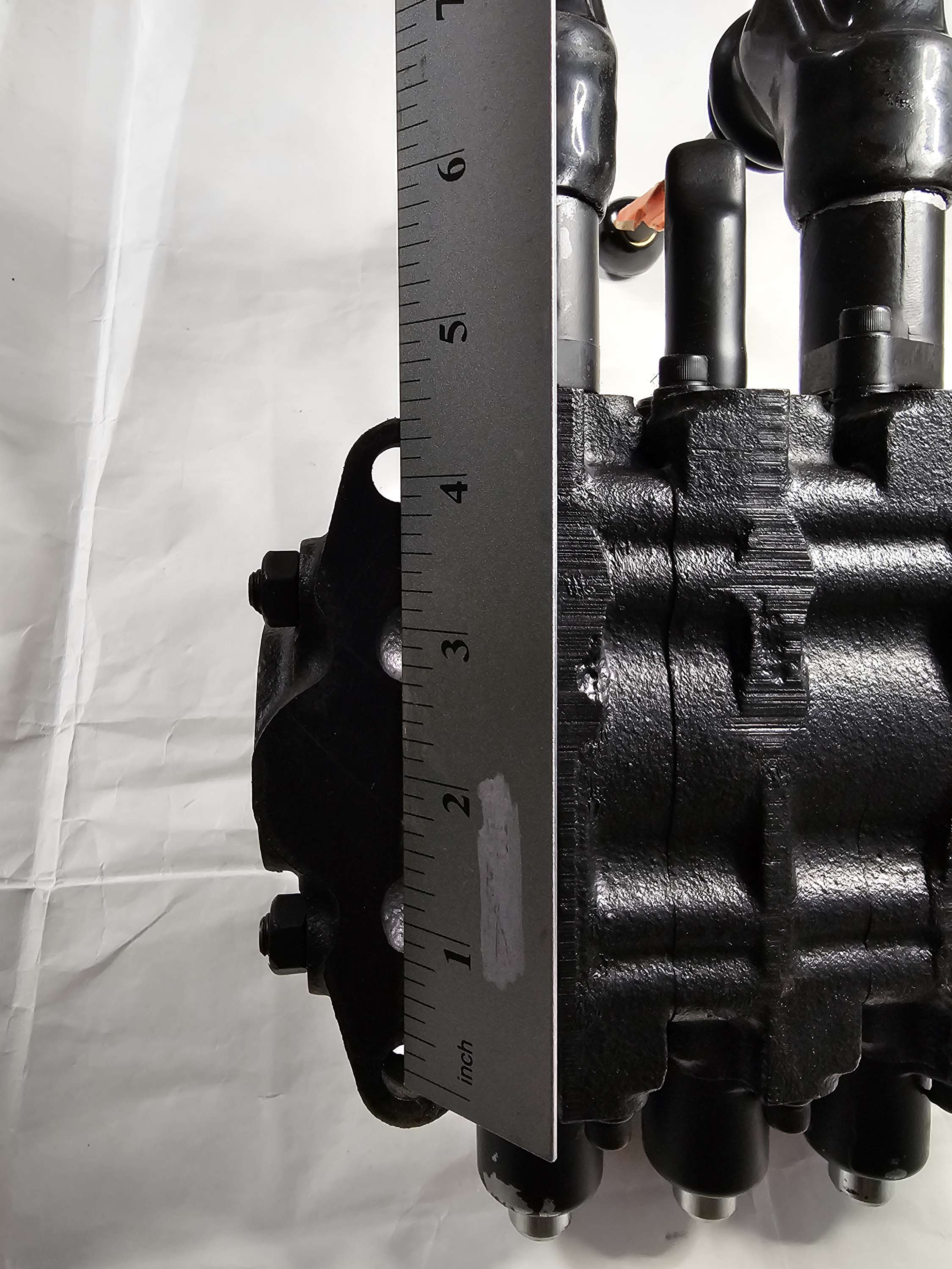 Close-up of a mechanical component with a ruler for scale on a white background