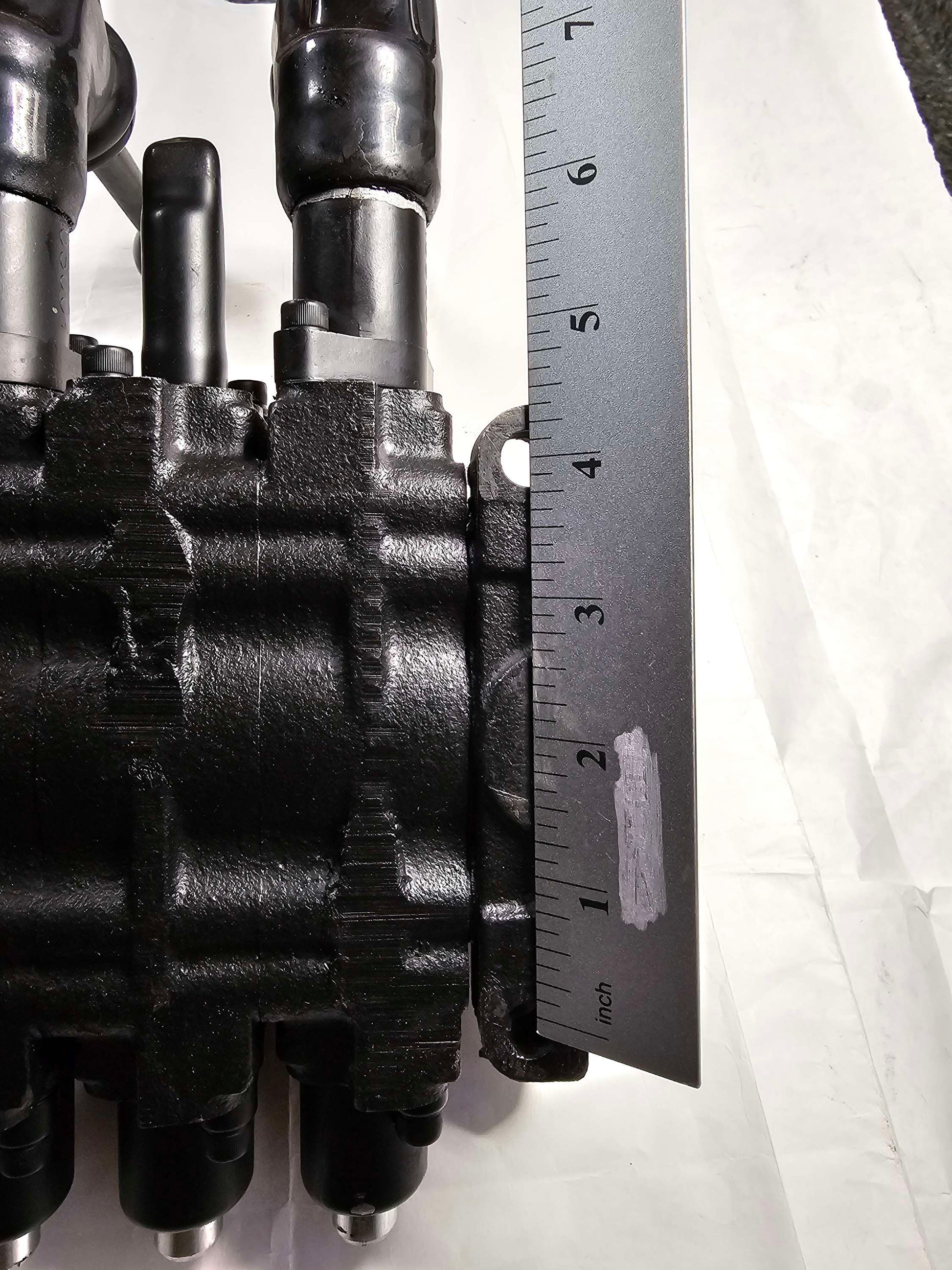 Close-up of mechanical components with a ruler for scale on a white background